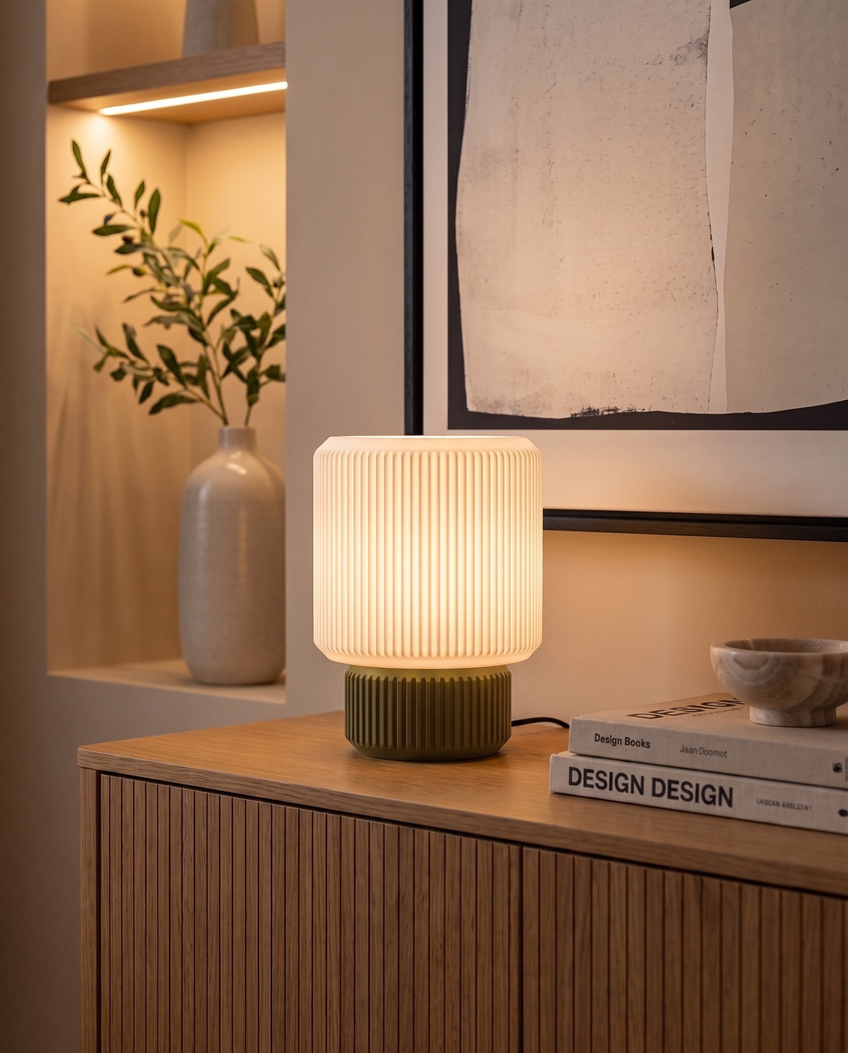 Lámpara Ágora con base Musgo, encendida sobre un aparador de madera