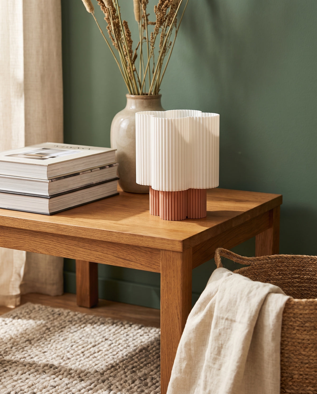 Lámpara Trébol con base Terracota sobre una mesa de madera junto a una pared verde