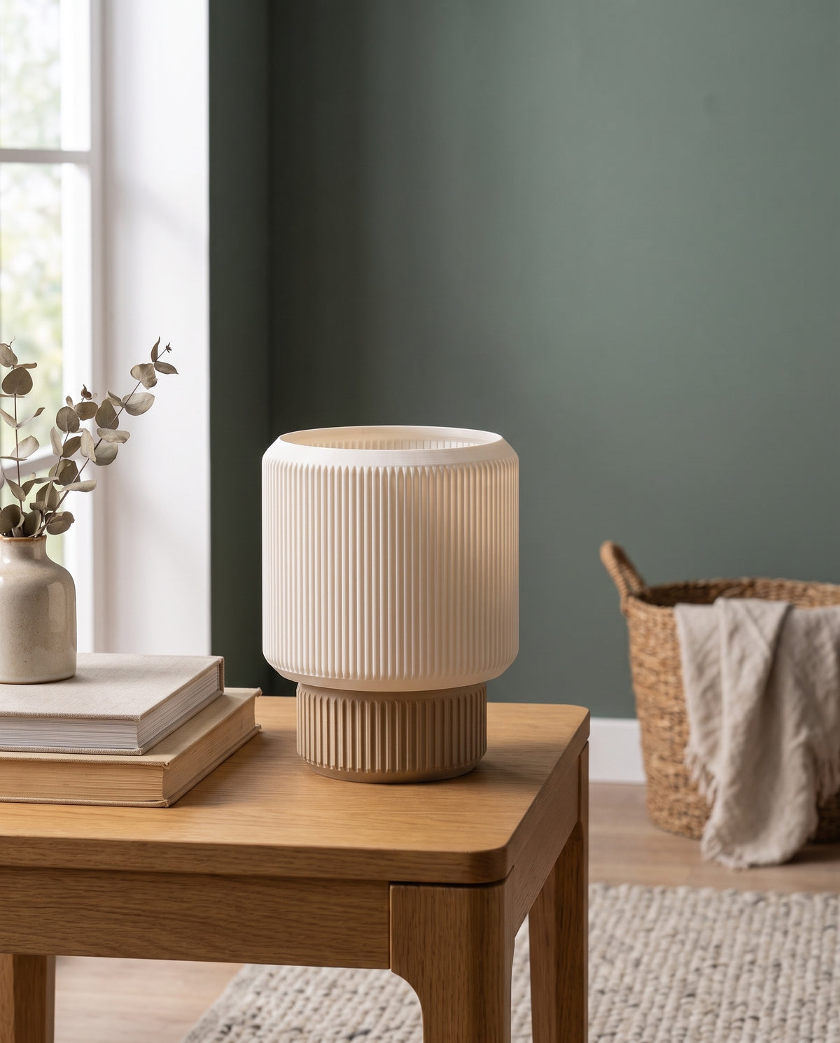 Lámpara Ágora con base Arena sobre una mesa de madera junto a una pared verde