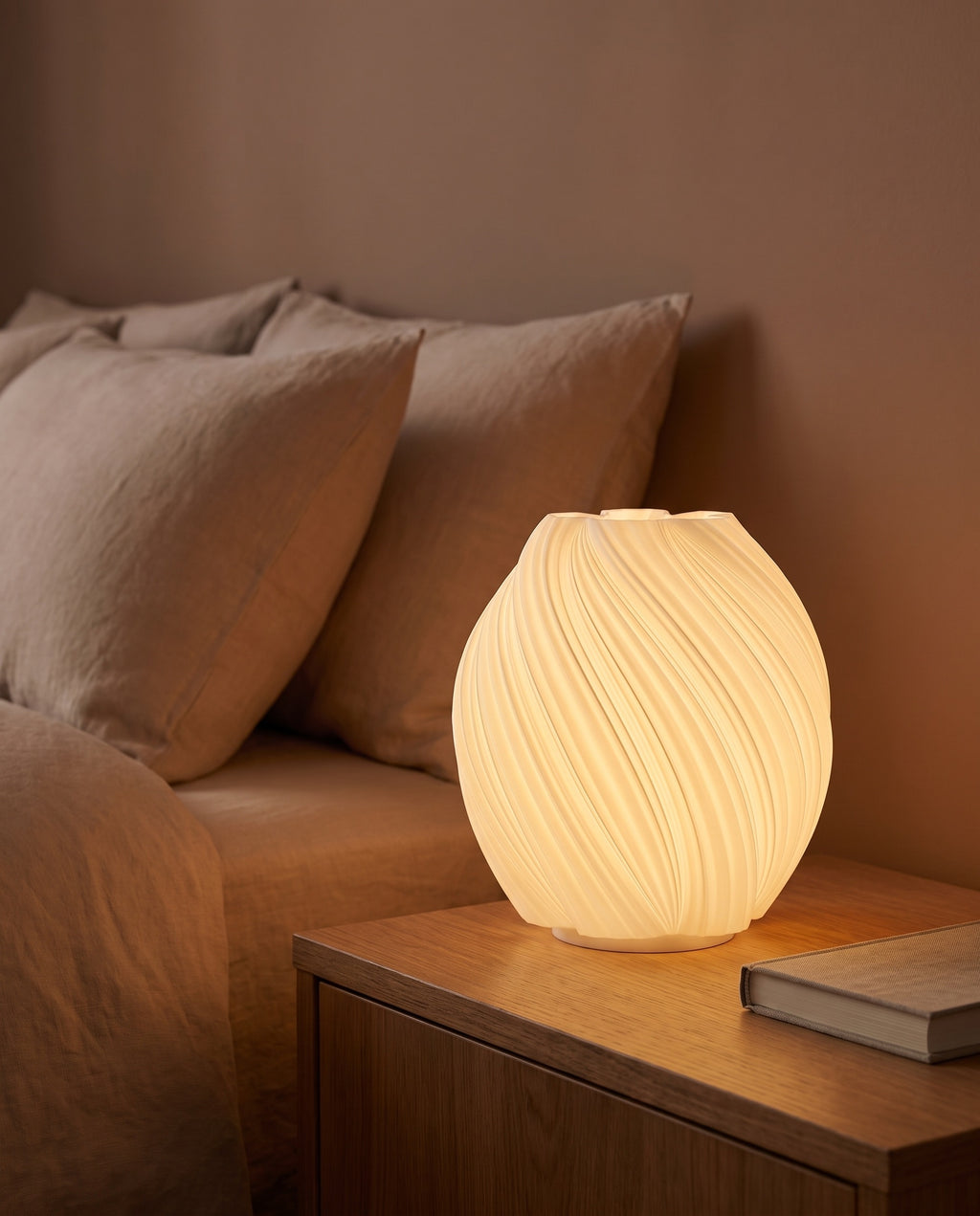 Lámpara Capullo encendida sobre una mesa de noche de madera